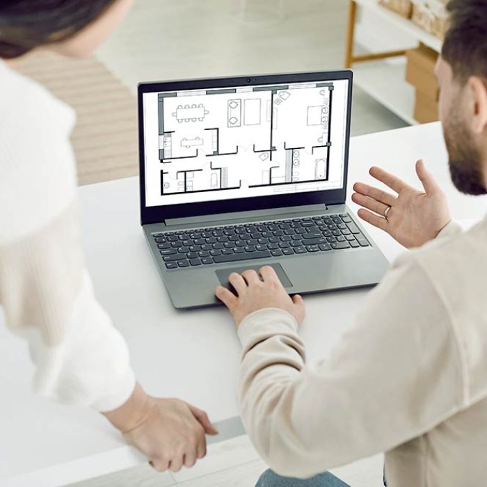 Family couple or architect coworkers looking at blueprint on laptop. Young man and woman using notebook computer, looking at house plan and discussing future house design together
