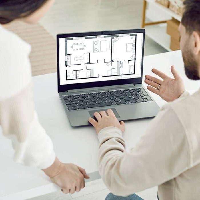 Family couple or architect coworkers looking at blueprint on laptop. Young man and woman using notebook computer, looking at house plan and discussing future house design together